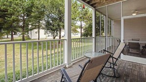 A covered porch with a table and chairs, a railing, and a view of a grassy yard and trees. - Bear Trap Dunes 1st floor condo w/ central AC, private W/D, and gas fireplace (Ocean View)