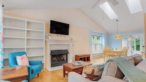 Una sala de estar con chimenea, televisor y comedor con sillas y una mesa.