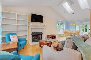 A living room with a fireplace, a television, and a dining area with chairs and a table. - Clearwater - Jamestown Cir | House in Frankford (Frankford)