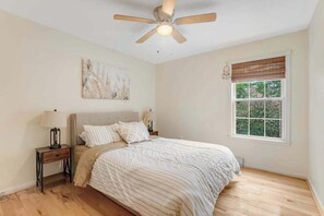 A bedroom with a bed, a nightstand, a ceiling fan, a window with blinds, and a wall-mounted artwork. - Clearwater - Jamestown Cir | House in Frankford (Frankford)