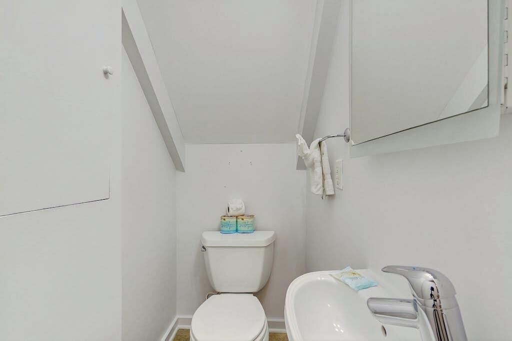 A small, white bathroom with a toilet, a sink, and a mirror.