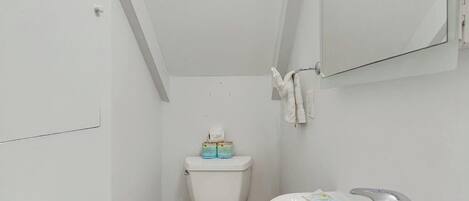A small, white bathroom with a toilet, a sink, and a mirror.