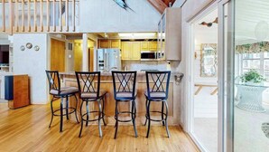 Una cucina moderna con pavimento in legno, un'area pranzo con quattro sedie e una grande decorazione a forma di pesce al muro.