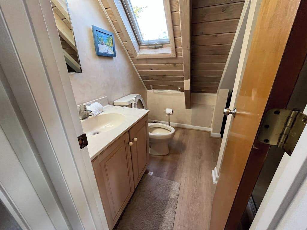 Une petite salle de bain comprenant un lavabo, des toilettes et une fenêtre située au-dessus des toilettes.