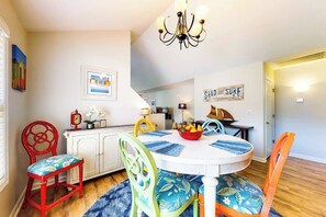 A dining area with a round table, chairs, a chandelier, and a sign that reads 'SAND AND SURF'. - Forest Reach home near beach with pool access & W/D - dog-friendly (Frankford)
