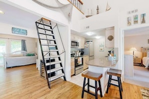 A modern kitchen with a central island, a staircase, and a dining area with stools. - Sea Colony West - Waterfront condo with pool, beach access, tennis, & W/D (Bethany Beach)