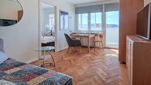Una camera moderna con un letto, un tavolo da pranzo con sedie, una TV e un'ampia finestra con vista.