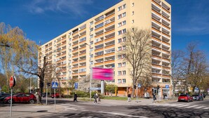 Un palazzo a più piani con balconi, un attraversamento pedonale e un segnale di parcheggio.