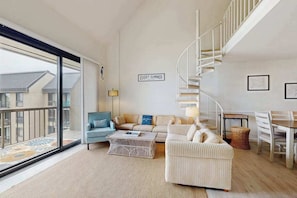 A modern living room with a sofa, coffee table, and a staircase. - Sea Colony condo with pools, tennis, beach, hot tub, gym, sauna, & balcony (Bethany Beach)