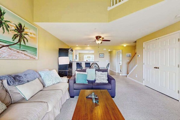 A living room with a sofa, coffee table, and a painting of a beach scene.