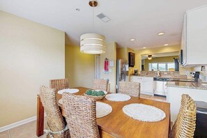 A dining area with a wooden table, wicker chairs, and a hanging light fixture.