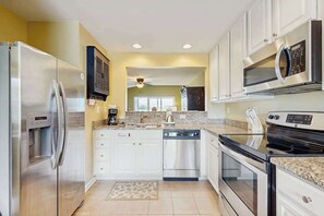 A modern kitchen with stainless steel appliances, white cabinets, and a granite countertop.