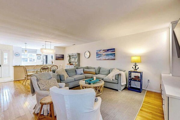 A spacious living room with a sofa, chairs, a round coffee table, and a small side table with a lamp.