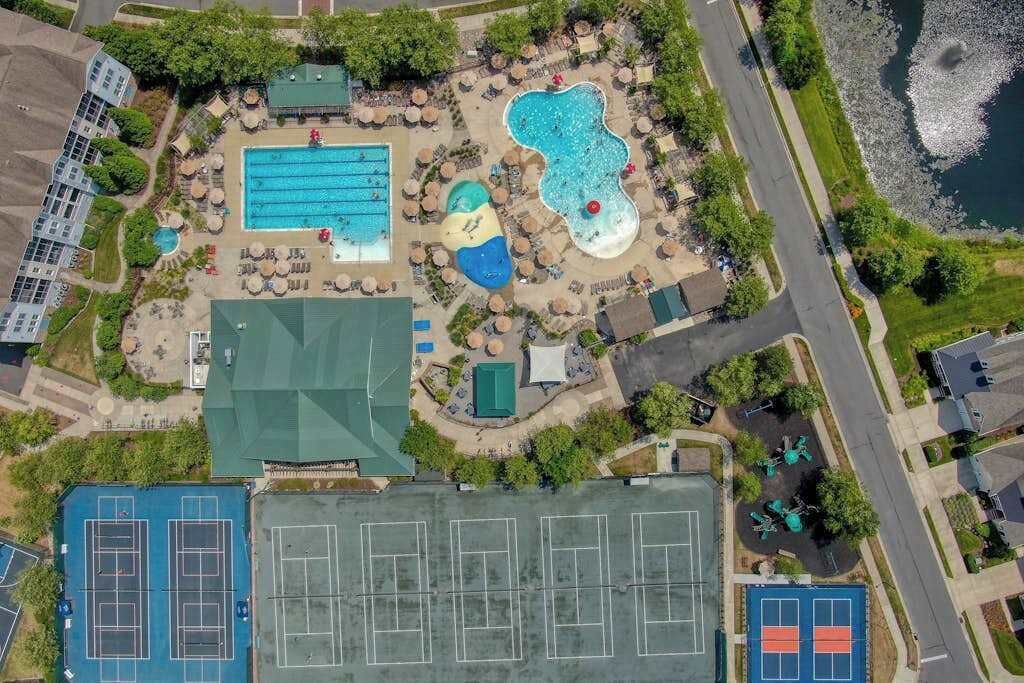 Vue aérienne d’un complexe hôtelier doté d’une piscine, de courts de tennis et d’une plage.