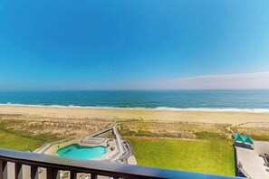 A beach view from a balcony overlooking a swimming pool and a sandy beach. - Sea Colony condo with balcony, pools, beach access, tennis & fitness centers (Bethany Beach)