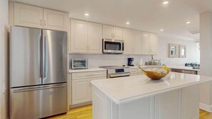 Una cocina moderna con armarios blancos, electrodomésticos de acero inoxidable y una isla central.