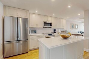 A modern kitchen with white cabinetry, stainless steel appliances, and a central island. - Sea Colony condo with balcony, pools, beach access, tennis & fitness centers (Bethany Beach)