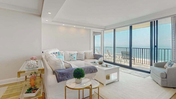 Una sala moderna con sofá, mesa de centro y vista al mar.