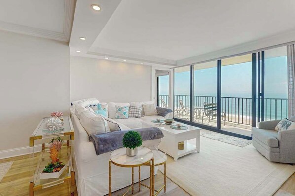 A modern living room with a sofa, coffee table, and a view of the sea. - Sea Colony condo with balcony, pools, beach access, tennis & fitness centers (Bethany Beach)