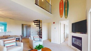 Un salón espacioso con chimenea, un comedor y una escalera que lleva a un nivel superior.
