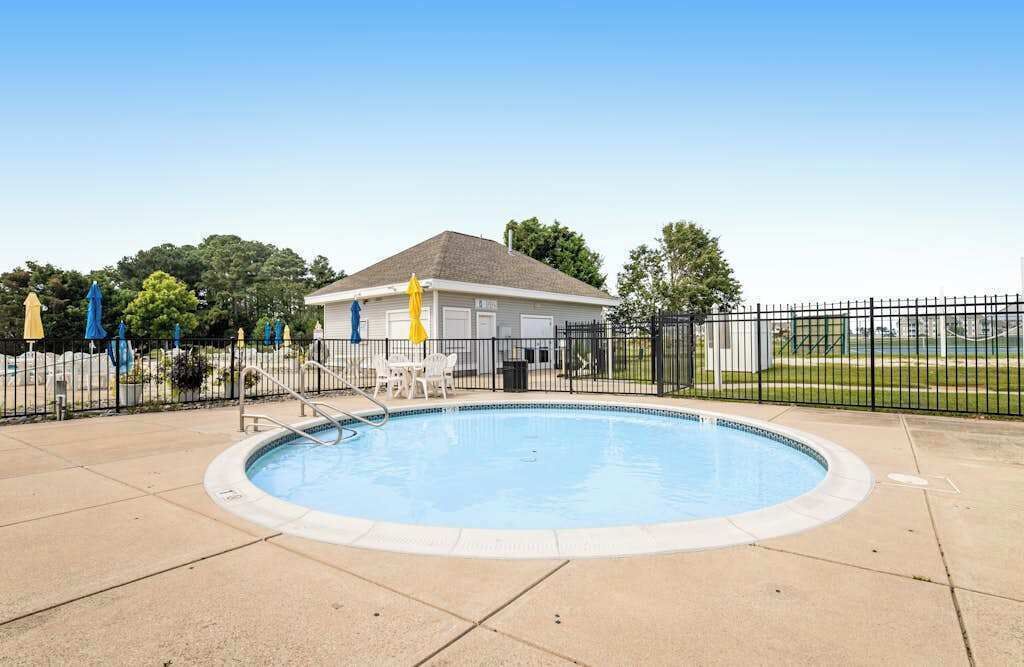 A swimming pool with a fenced area, a covered structure, and a clear sky.