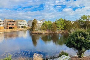 A residential area with a calm river, houses with balconies, and trees. - Town of Bethany Beach home on the canal with balcony & AC (Bethany Beach)