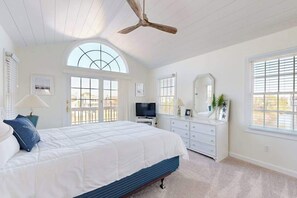 A bedroom with a bed, a ceiling fan, a TV, a dresser, and a window. - Town of Bethany Beach home on the canal with balcony & AC (Bethany Beach)