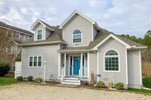 A two-story house with a front porch, a blue door, and a mailbox. - Spacious Salt Pond home with private deck & pool/hot tub/tennis access (Bethany Beach)