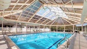 Ein Hallenbad mit Glasdach, deutlich abgegrenzten Bahnen und einem Poolbereich.