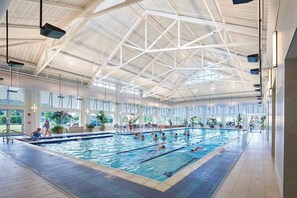 Ein Hallenbad mit hoher Decke und großen Fenstern.