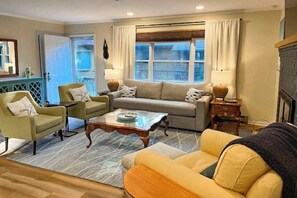 Ein Wohnzimmer mit einer Couch, zwei Sesseln, einem Couchtisch und einem Kamin.