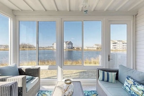 A room with a view of a lake, wicker furniture, and a table with a decorative item. - 1st-floor Bethany Bay condo with bay views & on-site golf/pool/tennis (Ocean View)