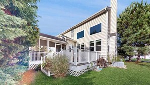 Une maison à deux étages avec un porche à l’avant et une petite terrasse.