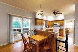 Una cocina moderna con armarios de madera, una isla central y un comedor con sillas de madera.