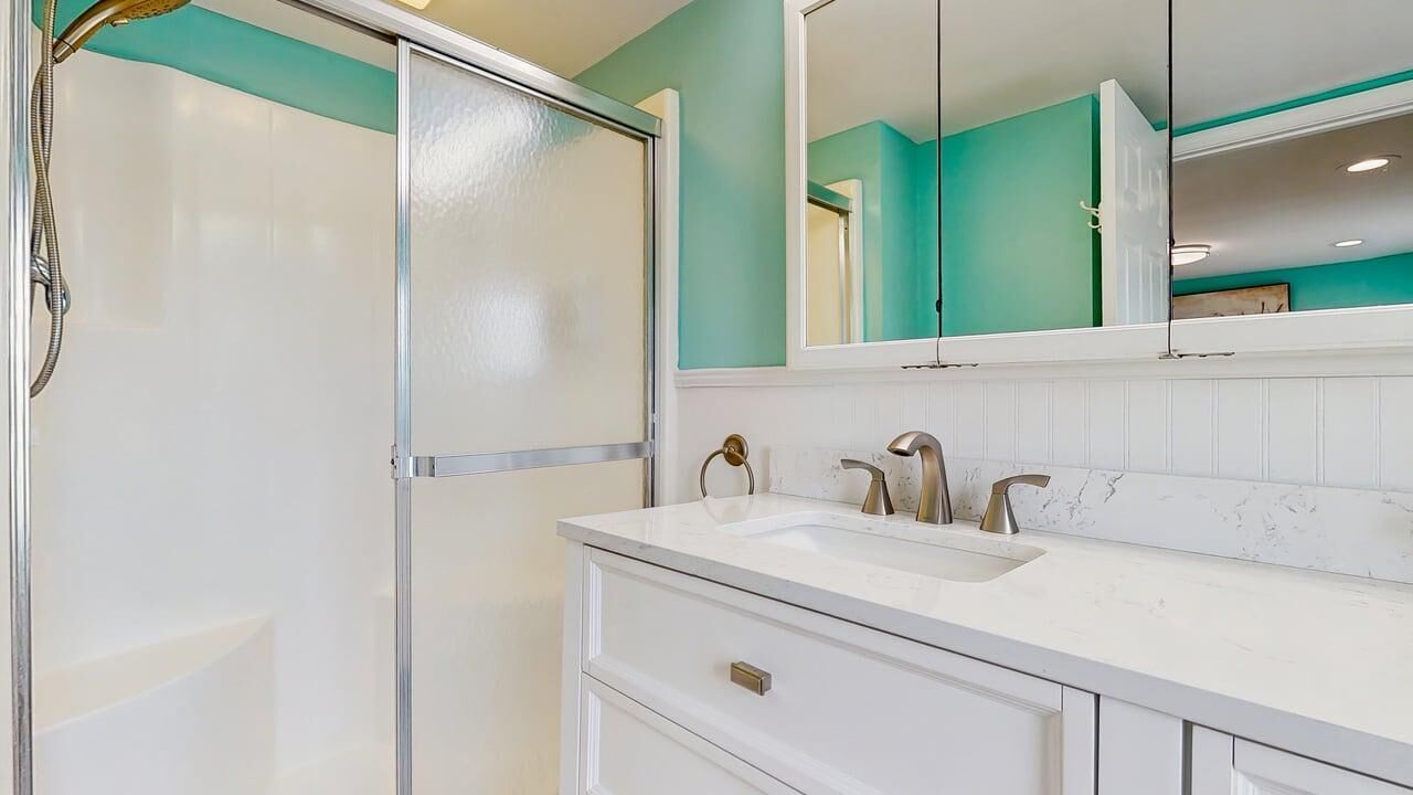 A bathroom with a shower, a sink, and a mirror.