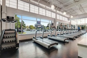 Een sportschool met meerdere loopbanden, een stair climber en grote ramen.