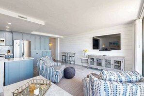 A modern kitchen with light blue cabinets, a central island, and a dining area with a white table and chairs. - Sea Colony Oceanfront 6th floor condo w/free WIFI, pool & balcony w/ocean view (Bethany Beach)