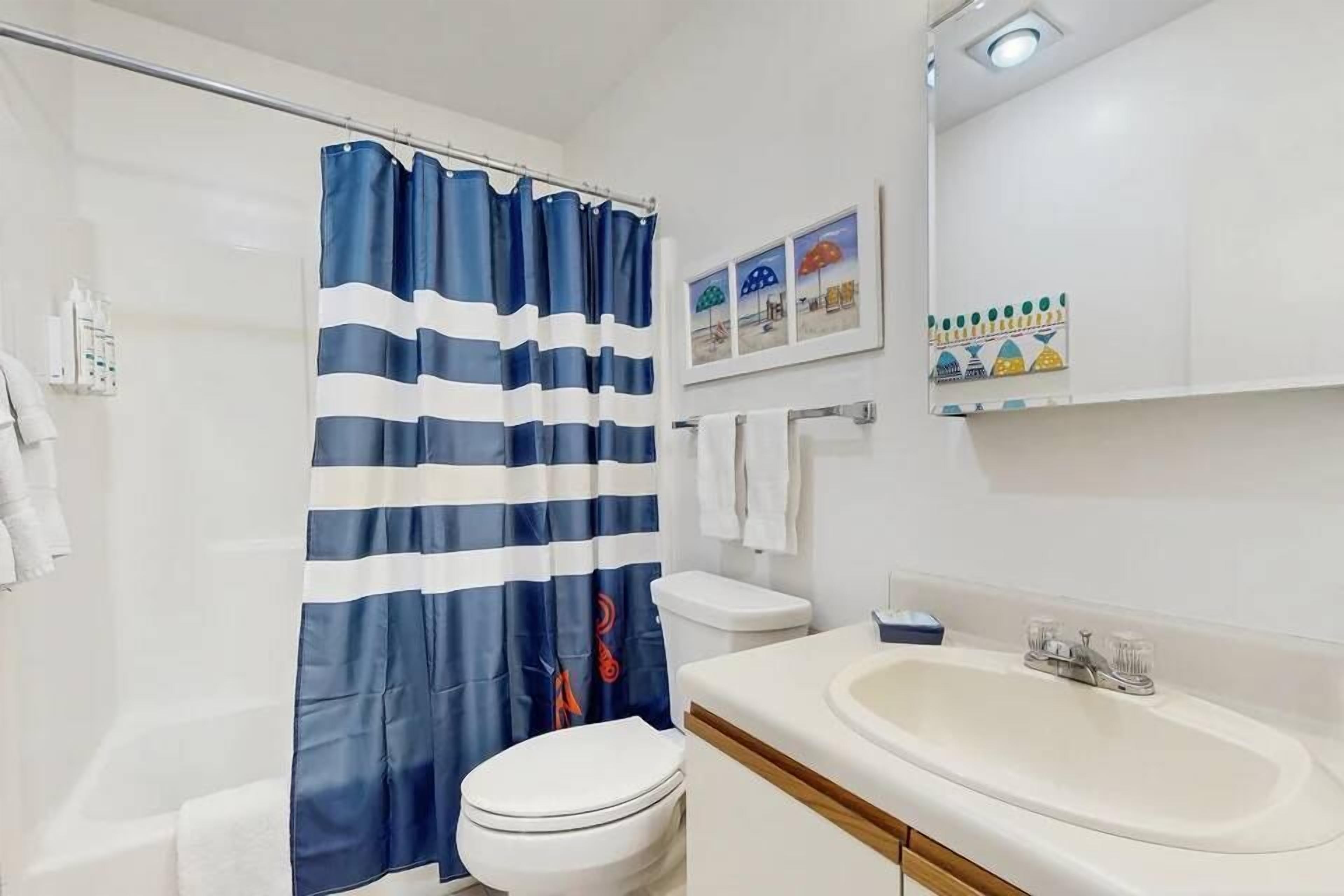Ein Badezimmer mit Duschvorhang, Toilette, Waschbecken und Handtuchhalter.
