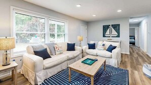 Ein modernes Wohnzimmer mit zwei weißen Sofas, einem Couchtisch und einer Lampe.