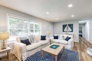 A modern living room with two white sofas, a coffee table, and a lamp. - Mill Run Estates home w/free WIFI, W/D, just minutes to the beach (Ocean View)