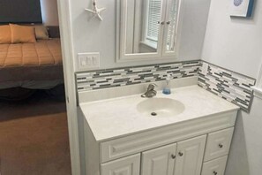 Une salle de bain avec un meuble-lavabo blanc, un évier et un miroir.