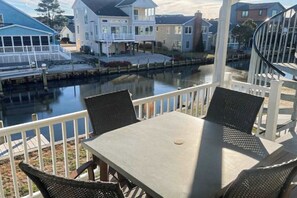 Une propriété située au bord de l’eau, avec une table et des chaises, un quai et des maisons en arrière-plan.