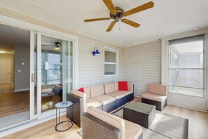 A sunlit room with a ceiling fan, sliding glass doors, a sofa, a small table, and wicker furniture. - Bethany Meadows townhouse w/shared pool, tennis, close to beach (Frankford)