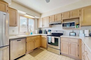Eine Küche mit Holzschränken, einem Edelstahl-Kühlschrank, einer Mikrowelle, einem Backofen und einem Toaster.