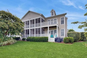 A two-story house with a covered porch, a small tower-like structure, and a well-maintained lawn. - Bear Trap Dunes dog friendly condo with pools, hot tub, WiFi, central A/C (Ocean View)