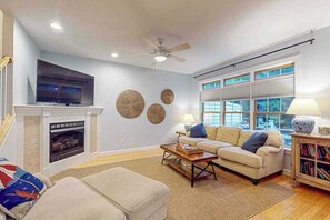 A living room with a fireplace, a sofa, a coffee table, and a bookshelf. - Ocean Mist townhouse with deck, grill, bikes, WIFI & W/D (Ocean View)