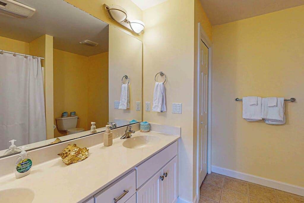 Un baño con lavabo, espejo, toallero y retrete.