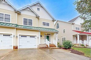 A two-story residential building with a green roof, white exterior, and a front porch. - Ocean Mist townhouse with deck, grill, bikes, WIFI & W/D (Ocean View)