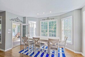 A dining area with a table and chairs, large windows, and a view of the outdoors. - Bethany Lakes house with a community pool, gym, tennis & free WiFi (Bethany Beach)