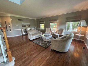 Ein geräumiges Wohnzimmer mit Holzdielen, Kamin, Essbereich und einer Treppe.